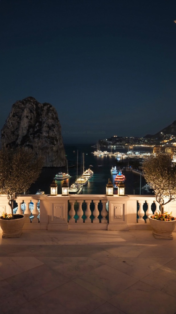 A lantern-lit stone terrace above a harbour at night.